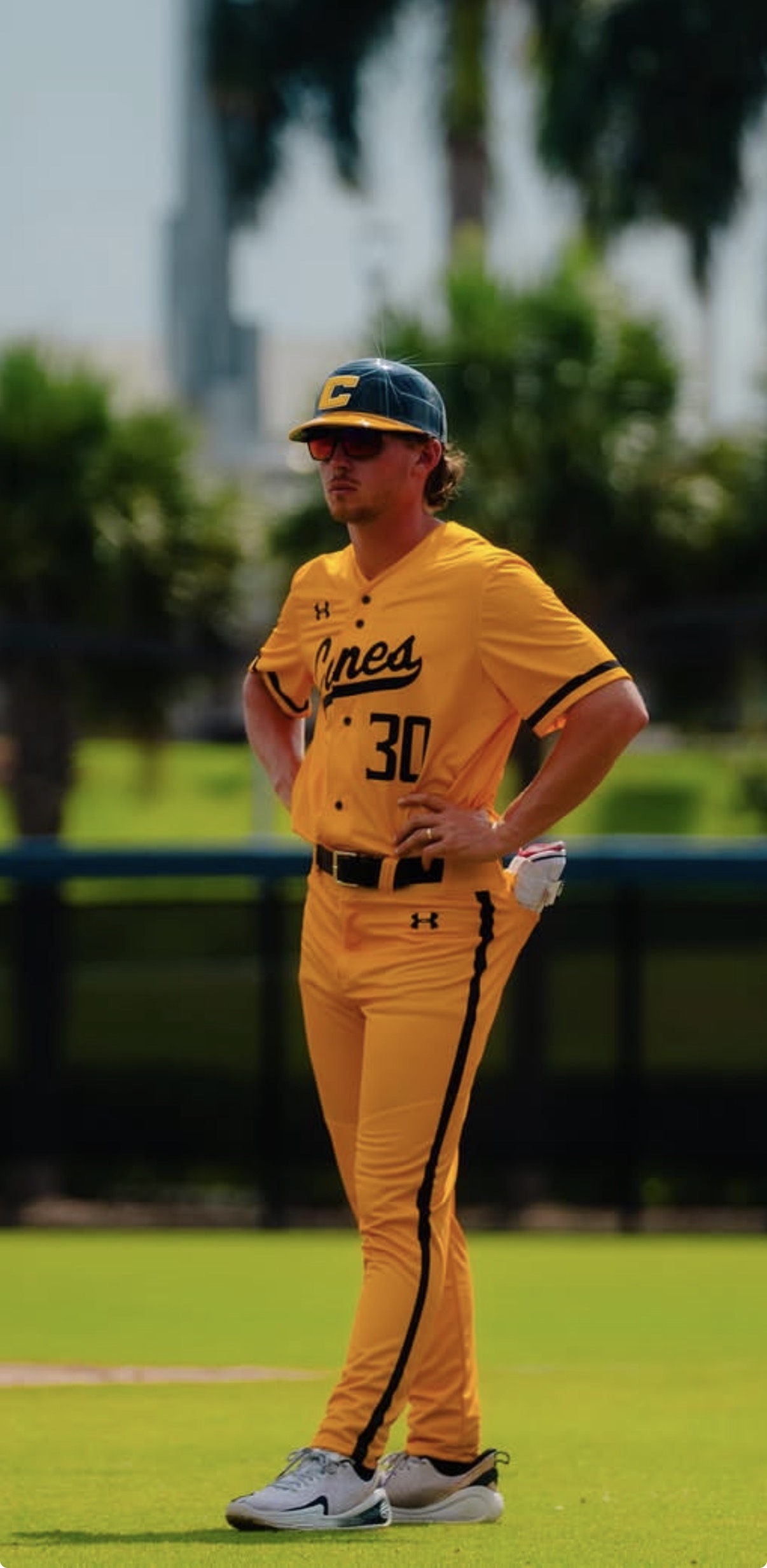 Tristan McAlister standing on a baseball field in a gold Canes uniform